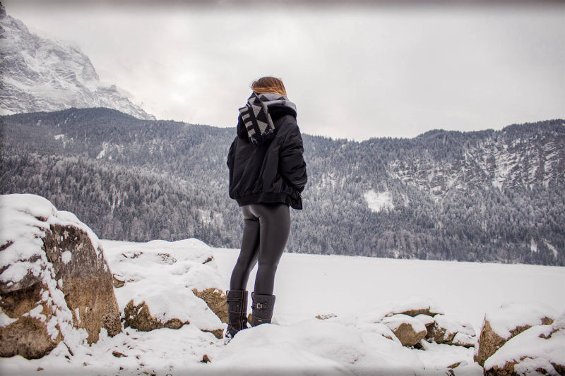 Nachdenklicher Moment in den Bergen mit einer Frau am Eibsee mit Schnee